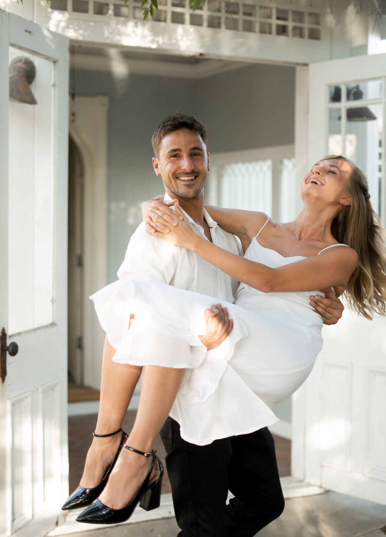 Man holding woman in Arms, walking out doorstep