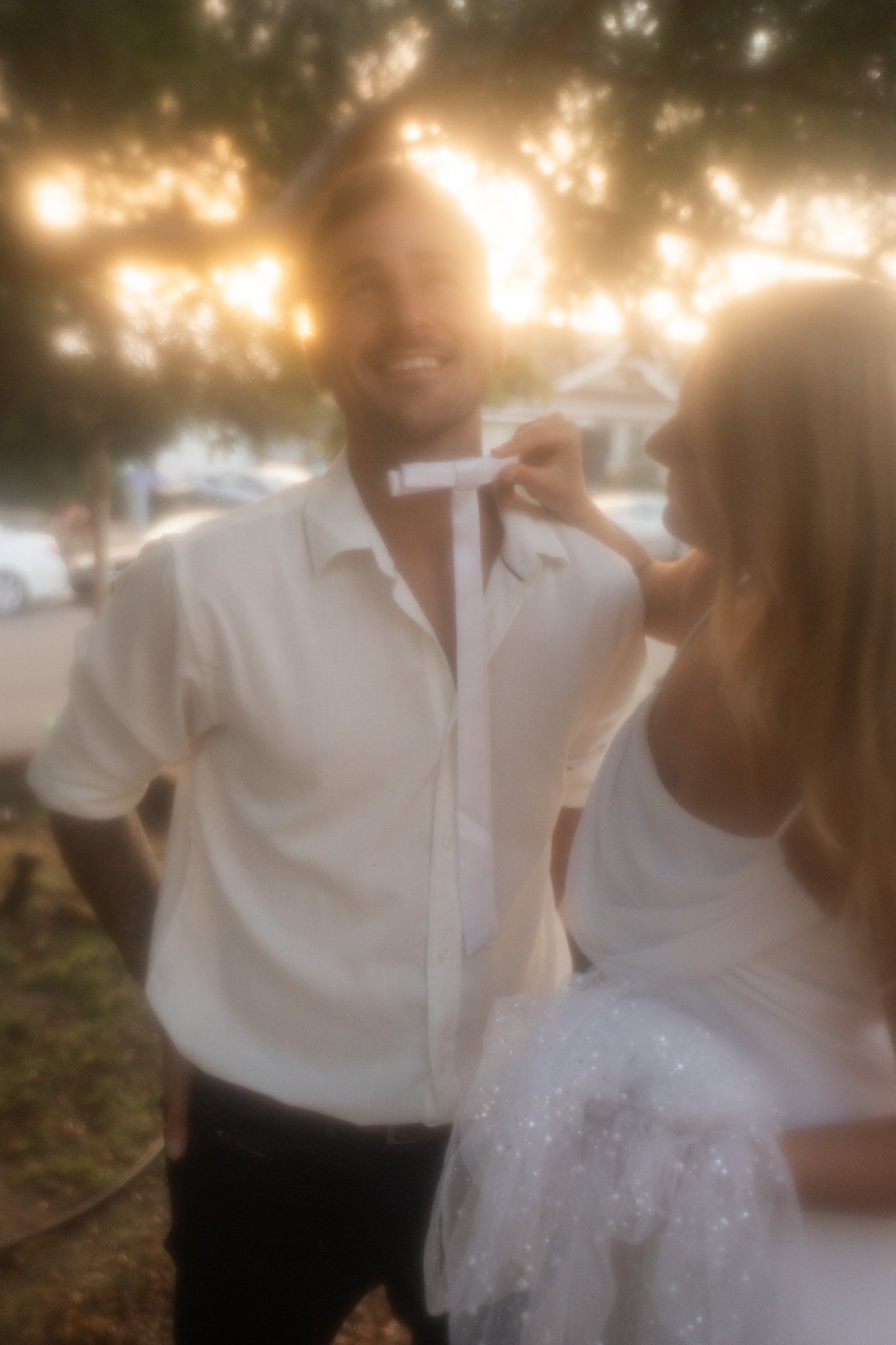 Woman holding up a tie infron of mans neck.