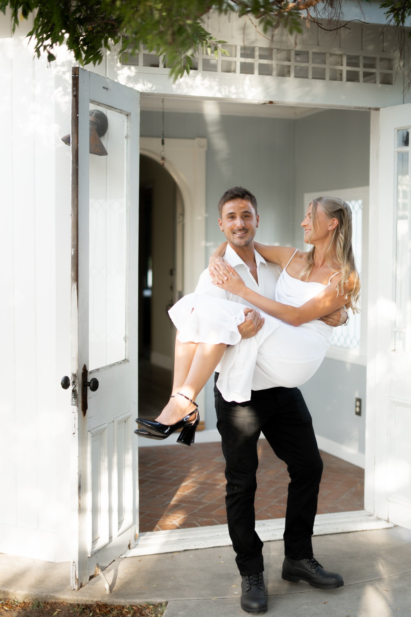 Man holding woman in Arms, walking out doorstep