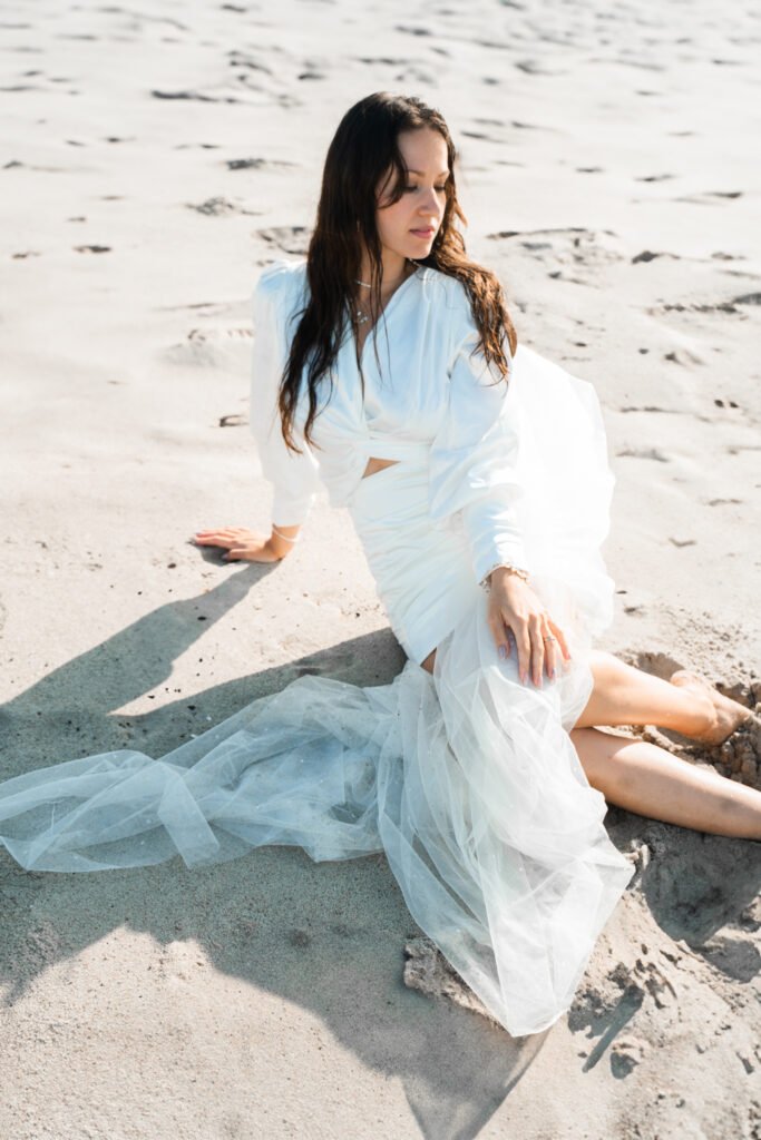 Woman laying in Sand in Malibu in weddingdress