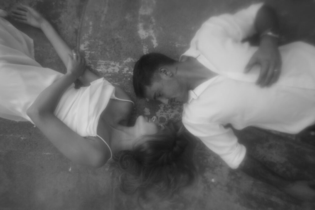 Man and Woman laying on ground, looking at each other.