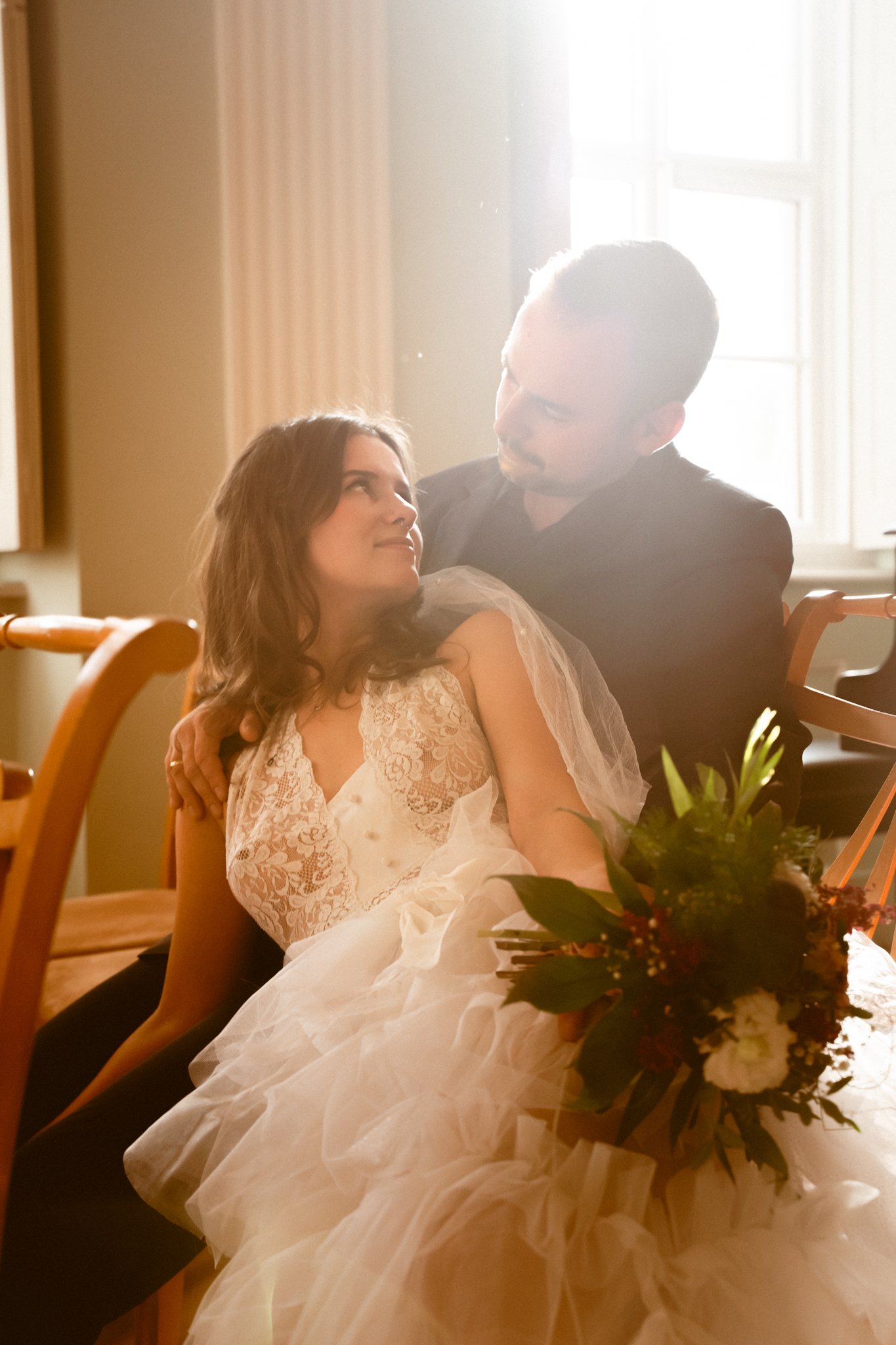 bride with flowers in her hand, looking at her Husband