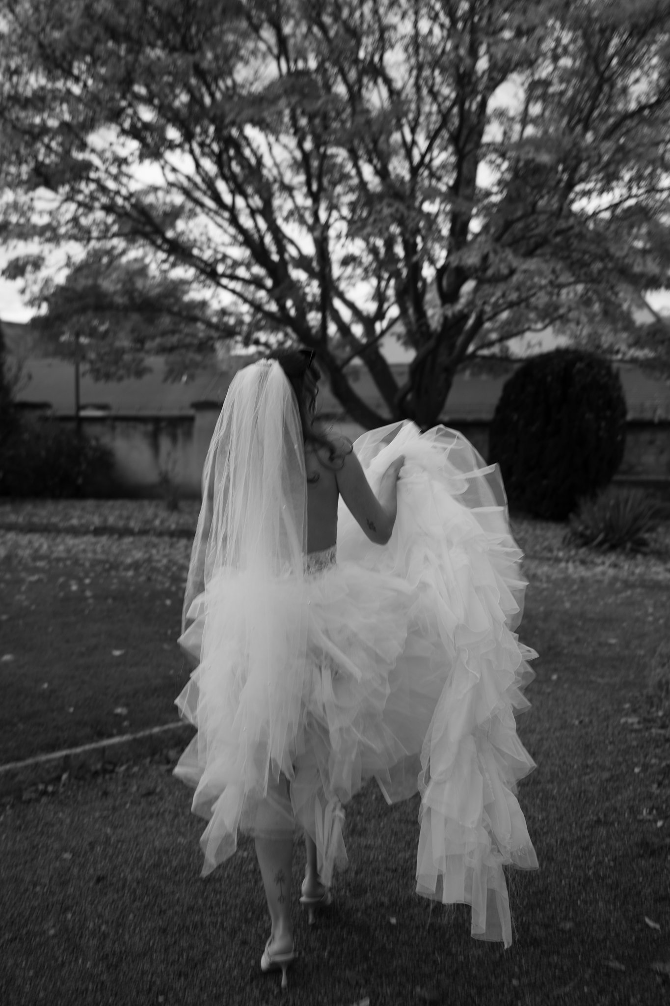 bride from behind walking and holding up her dress