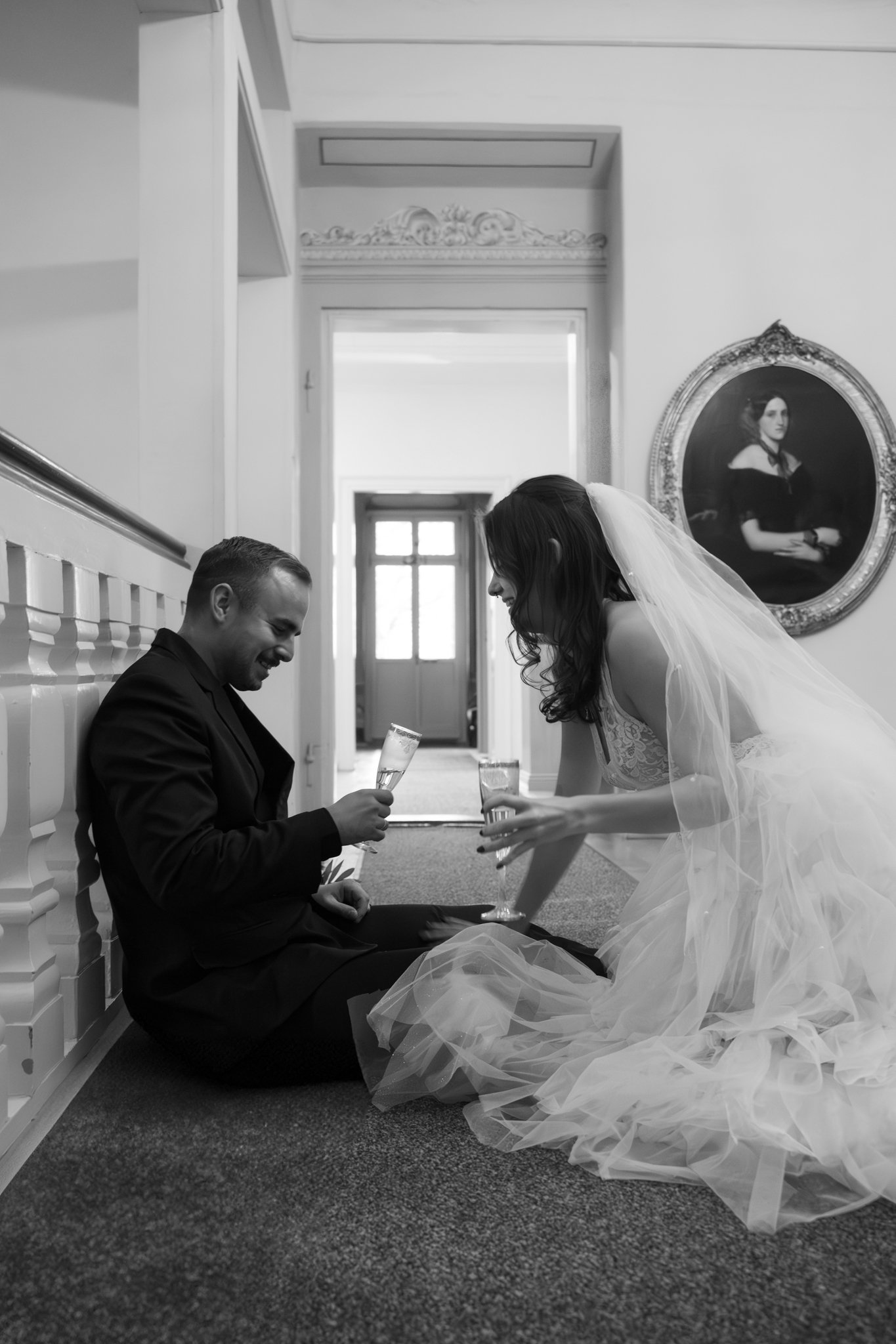 groom and bride sitting on the floor and cheersing with prosecco