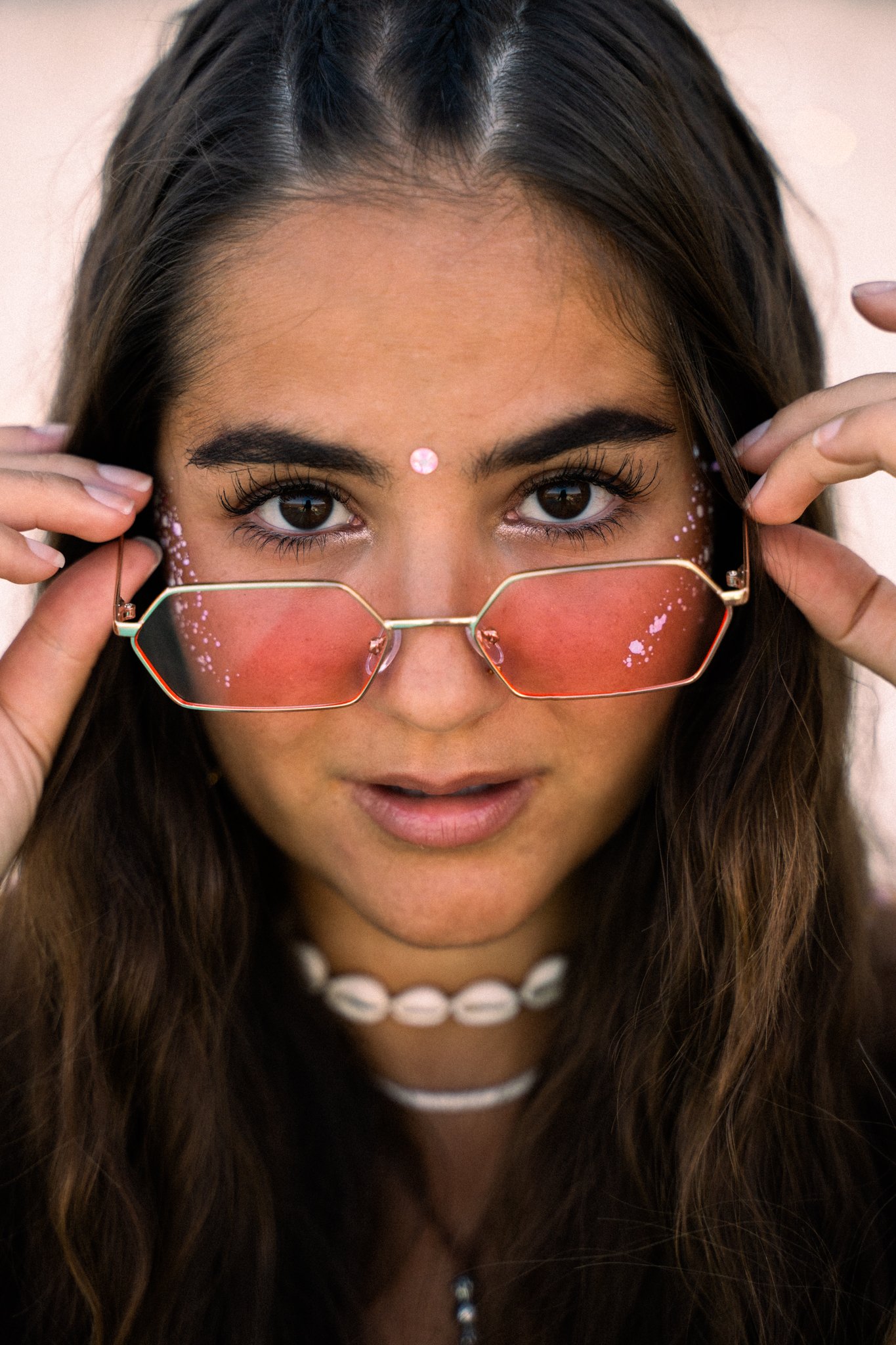 close up from girl wearing pink glasses and festival make up