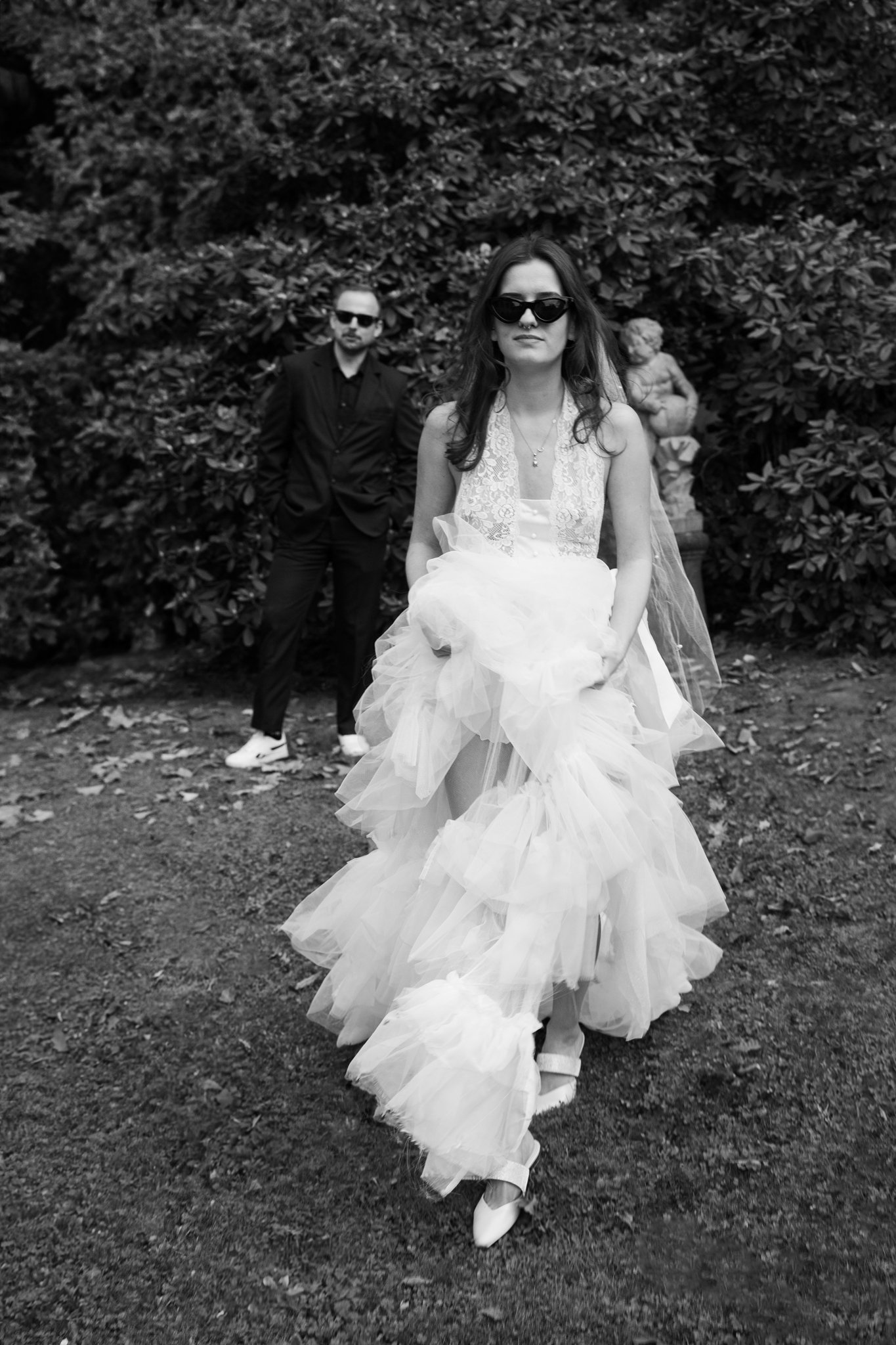 Bride (Clara) is walking to camera, nick standing in backround.