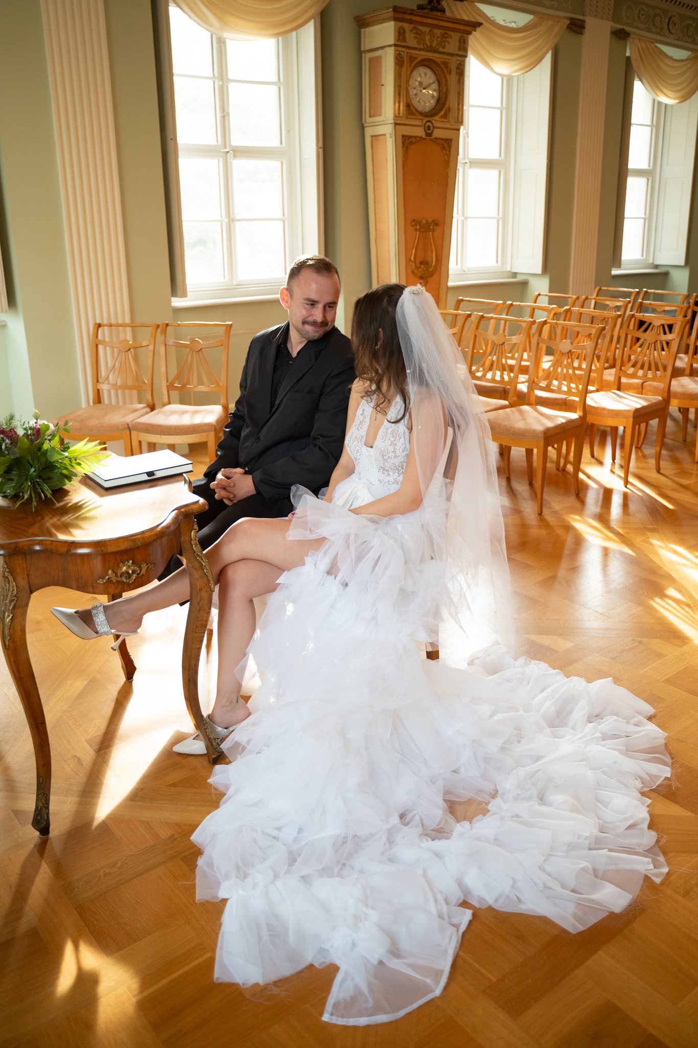 Nick and Clara saying vows and saying yes, sitting on chairs infront of priest.
